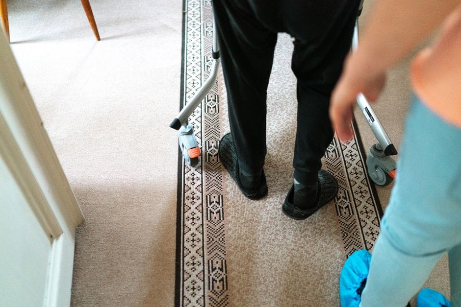 Nursing home caregiver helping an older resident walk